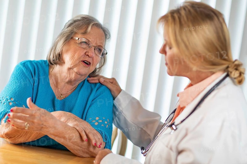 Senior adult woman talking with female doctor about sore arm