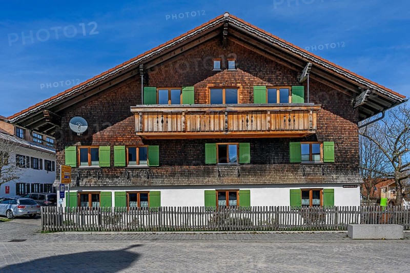 Fassade mit Holzschindeln und gruenen Fensterlaeden