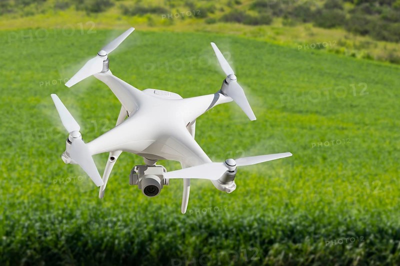 Drone unmanned aircraft flying and gathering data over country farmland