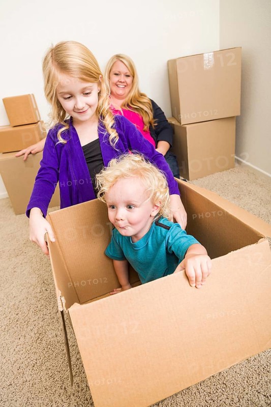 Playful young family in empty room playing with moving boxes