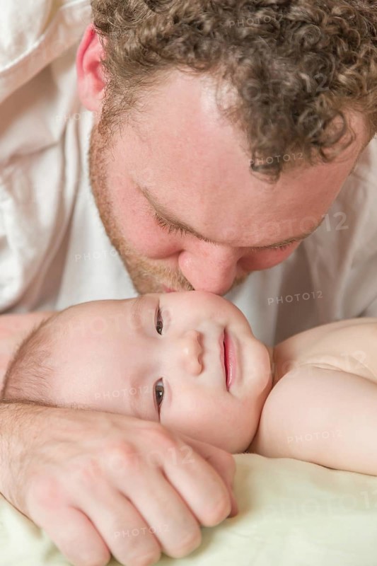 mixed-race chinese and caucasian baby boy laying in bed with his father