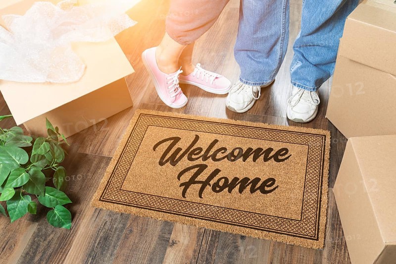 Man and woman unpacking near welcome home welcome mat