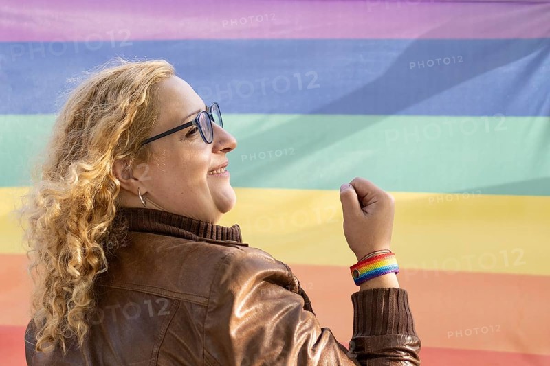 Portrait of a lesbian latin woman wearing lgbt wristband on a rainbow background