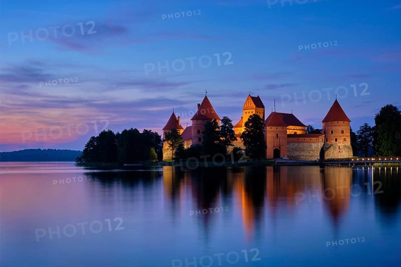 Trakai Island Castle in lake Galve illuminated in twilight reflecting in peaceful water
