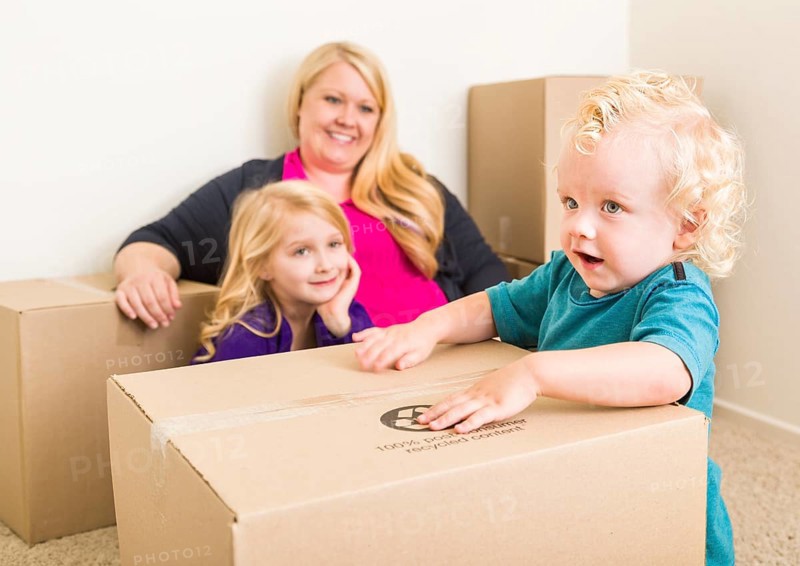 Playful young family in empty room playing with moving boxes