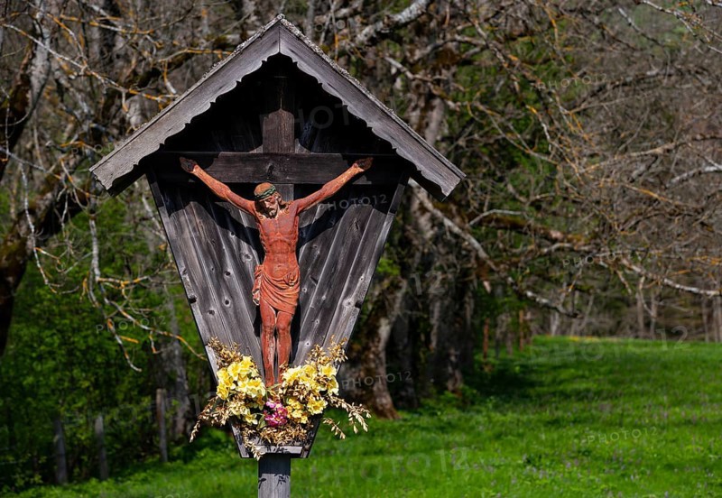 Geschnitztes Wegkreuz mit Blumenschmuck