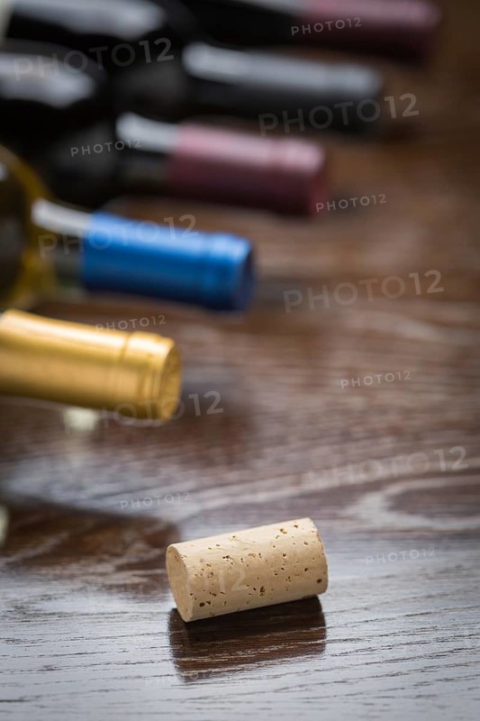 Wine bottles and cork on a reflective wood surface abstract