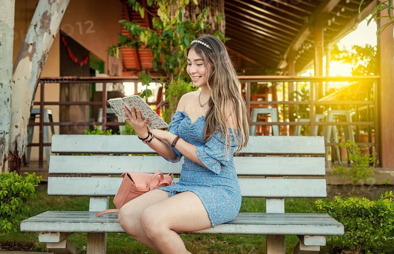 A cute girl sitting on a bench reading a book