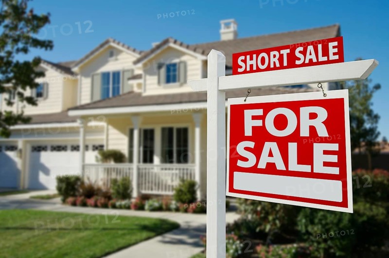 Short sale home for sale real estate sign in front of new house
