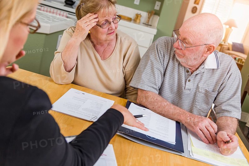 Senior adult couple going over documents in their home with agent at signing