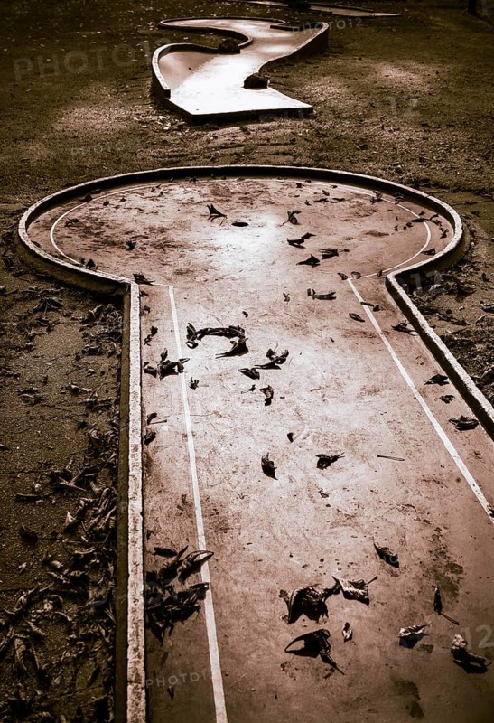 Verlassene Minigolfanlage mit Herbstlaub bedeckt