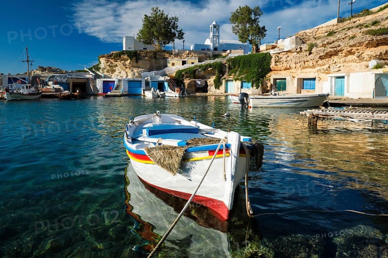 Fishing boats moored in crystal clear turquoise sea water in harbour in Greek fishing village of Mandrakia