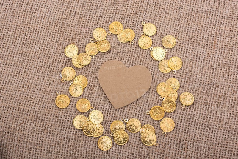Fake gold coins around heart shape made of paper