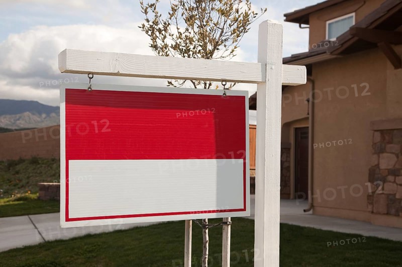 Blank red real estate sign in front of house ready for your own copy