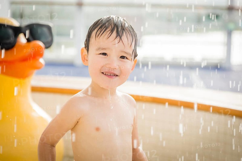 mixed-race boy having fun at the water park with large rubber duck in the background
