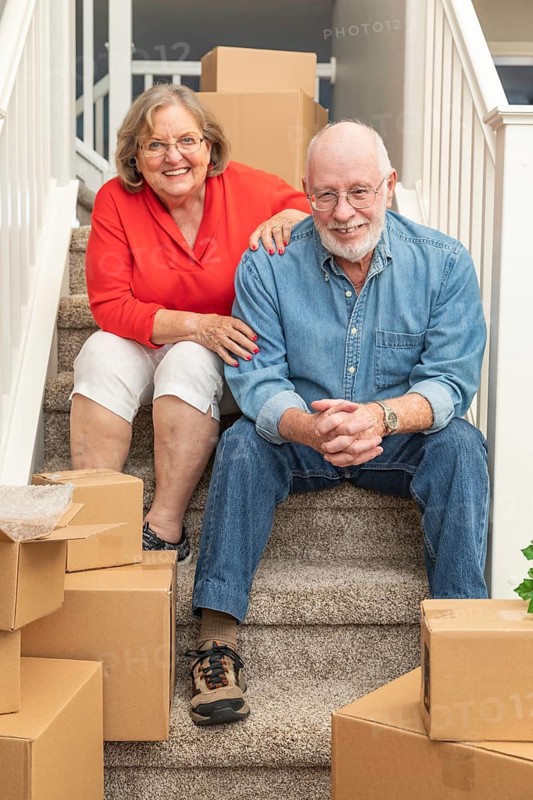 Senior couple resting on stairs surrounded by moving boxes