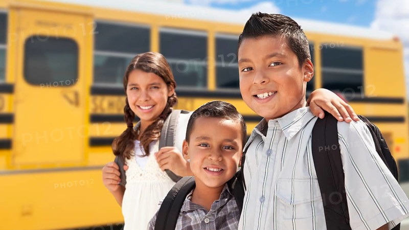 Young hispanic boys and girl walking near school bus