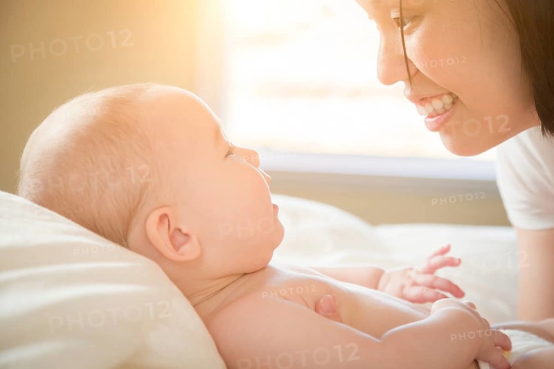 Young mixed-race chinese and caucasian baby boy laying in his bed with his mother