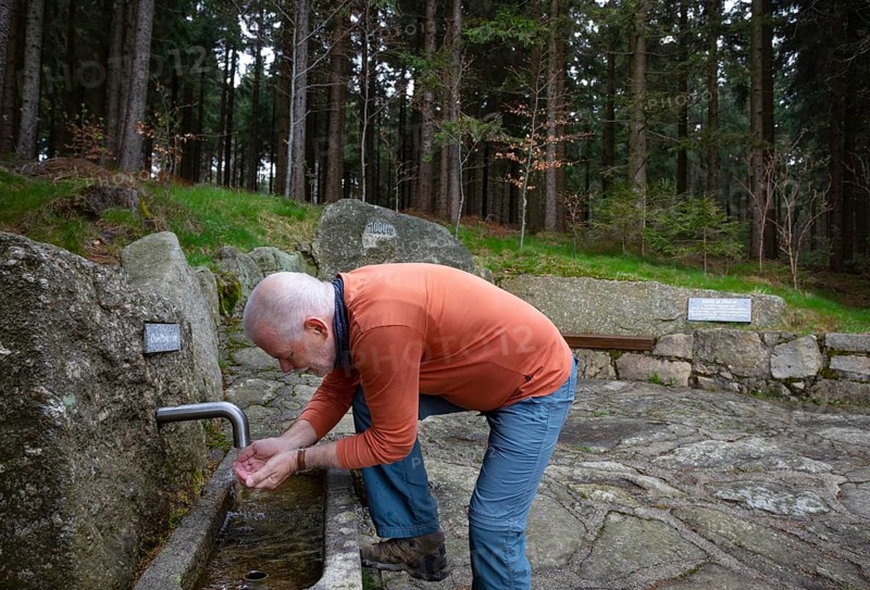 Hiker refreshes himself at the spring water fountain at the 1000 m square
