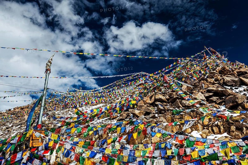 Tibetan prayer flags of Buddhism with Buddhist mantra on it on top of Himalayan pass Khardung La