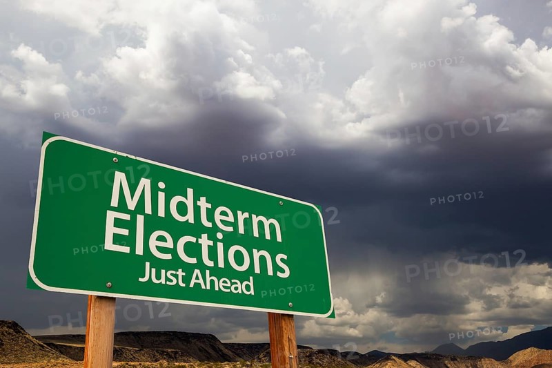 Midterm elections green road sign over dramatic clouds and sky