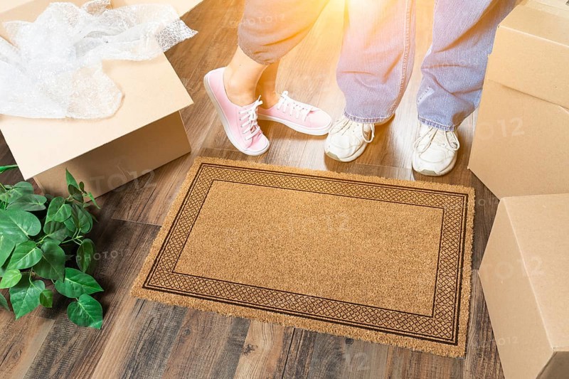 Man and woman standing near blank welcome mat