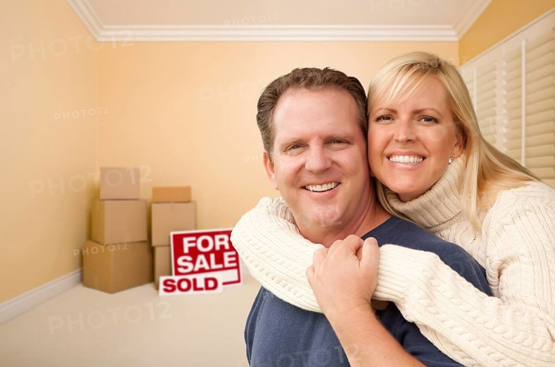 Happy affectionate couple in room of new house with only boxes on the floor