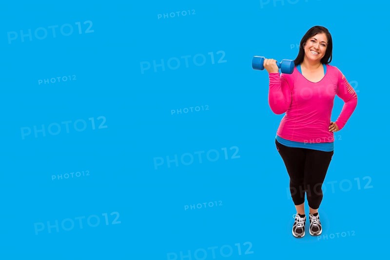 Middle aged hispanic woman in workout clothes holding dumbbell against A bright cyan blue background