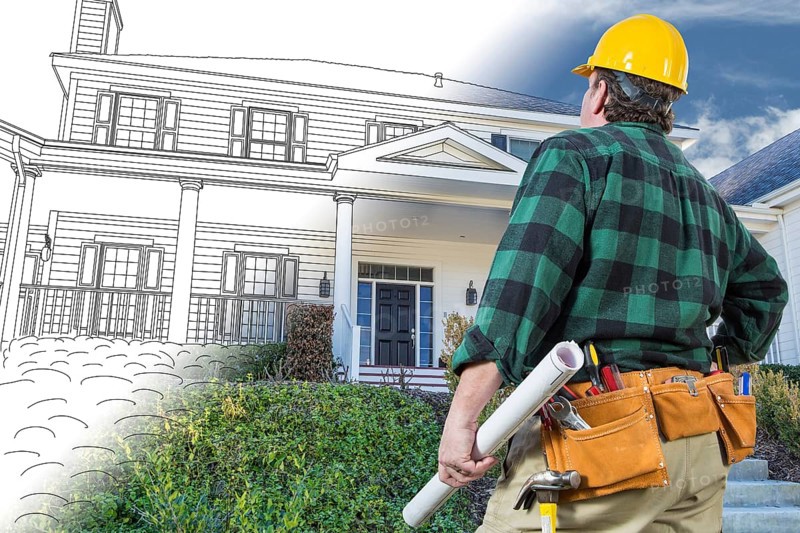 Male contractor with hard hat and tool belt looking at custom house drawing photo combination on white