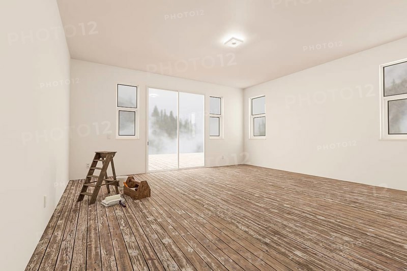 Ladder and painting equipment in raw unfinished room of house with blank white walls and worn wood floors