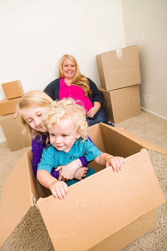 Playful young family in empty room playing with moving boxes