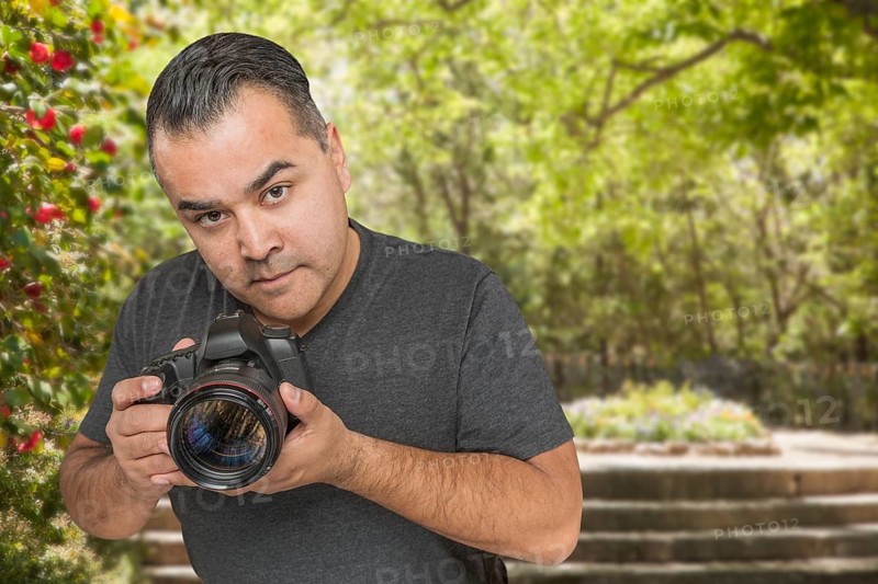 Hispanic young male photographer with DSLR camera outdoors