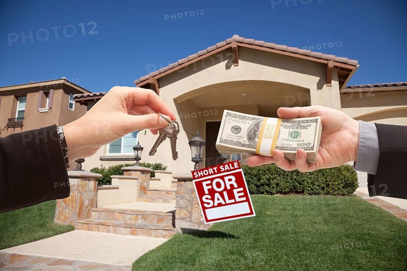 Handing over cash for house keys and short sale real estate sign in front of home