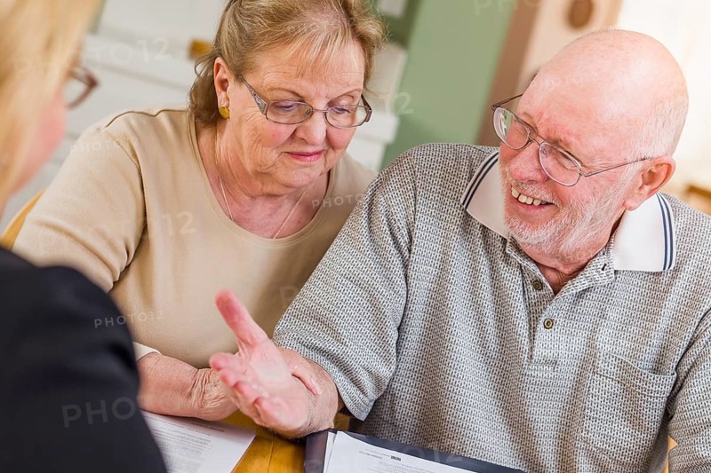 Senior adult couple going over documents in their home with agent at signing