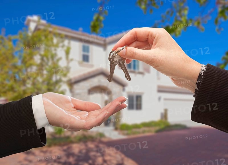Handing over the new house keys with home in the background