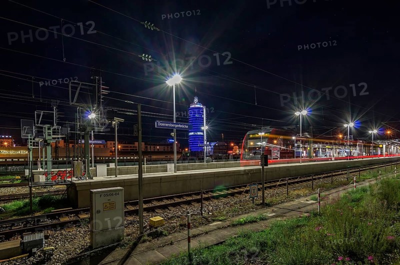 Arriving S-Bahn as long exposure at night in front of blue luminous tower