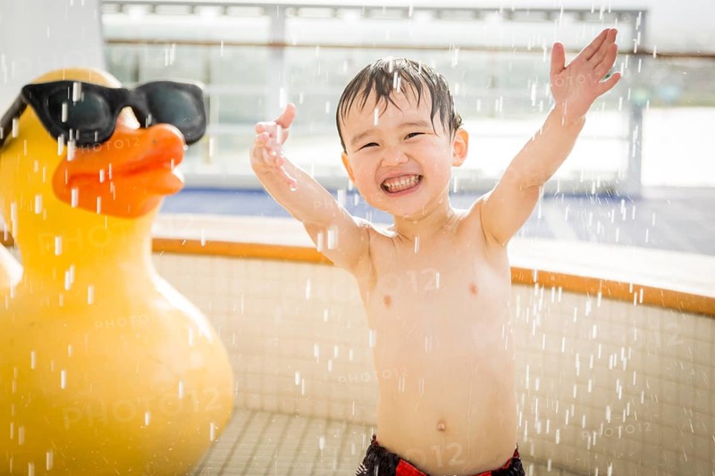mixed-race boy having fun at the water park with large rubber duck in the background