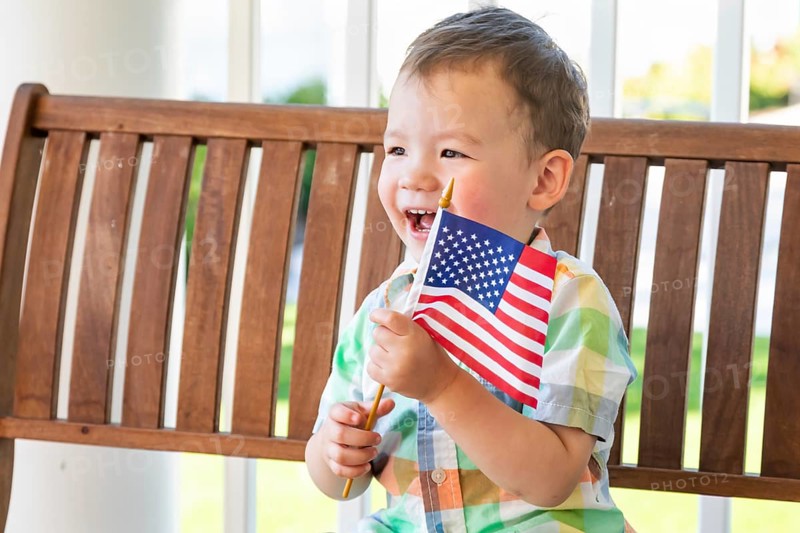 Young mixed-race chinese and caucasian boy playing with american flag