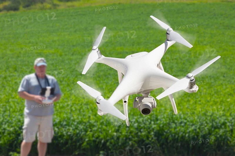 Pilot flying unmanned aircraft drone gathering data over country farmland field
