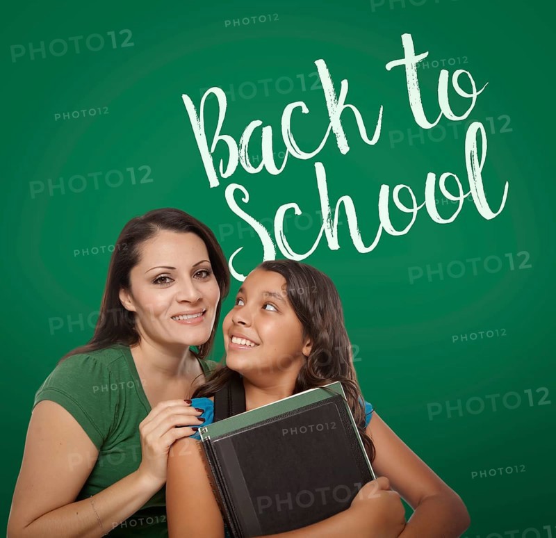 Back to school written on chalk board behind proud hispanic mother and daughter student