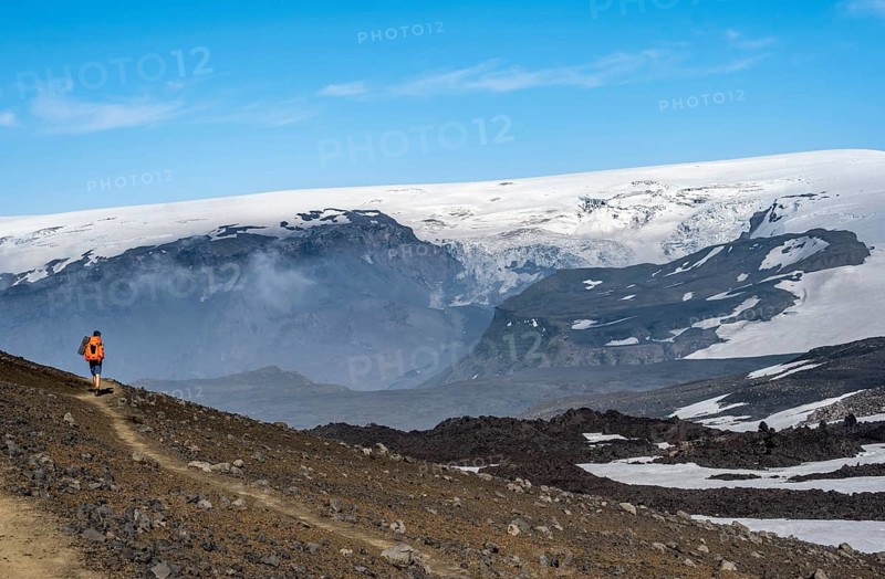 Hikers on trail through volcanic landscape