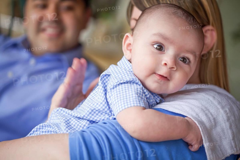 Happy attractive mixed-race couple burping their son