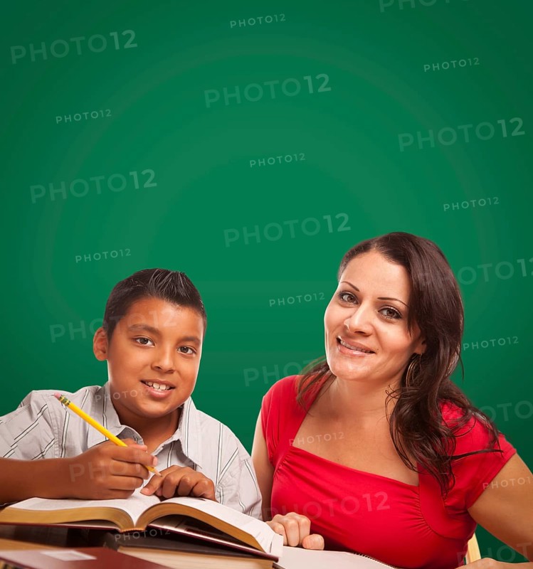 Blank chalk board behind hispanic young boy and famale adult studying