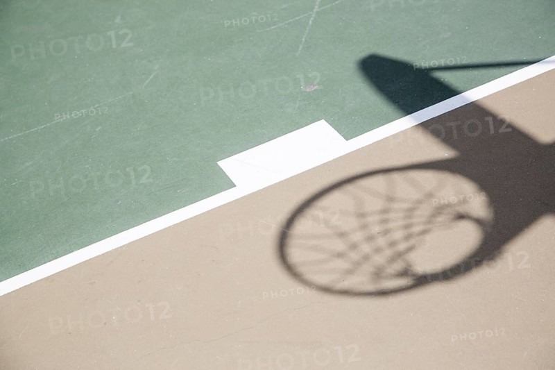 Abstract shadow of basketball hoop and net against court surface
