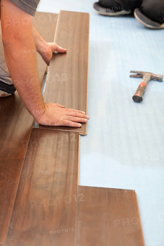 Man installing new laminate wood flooring abstract