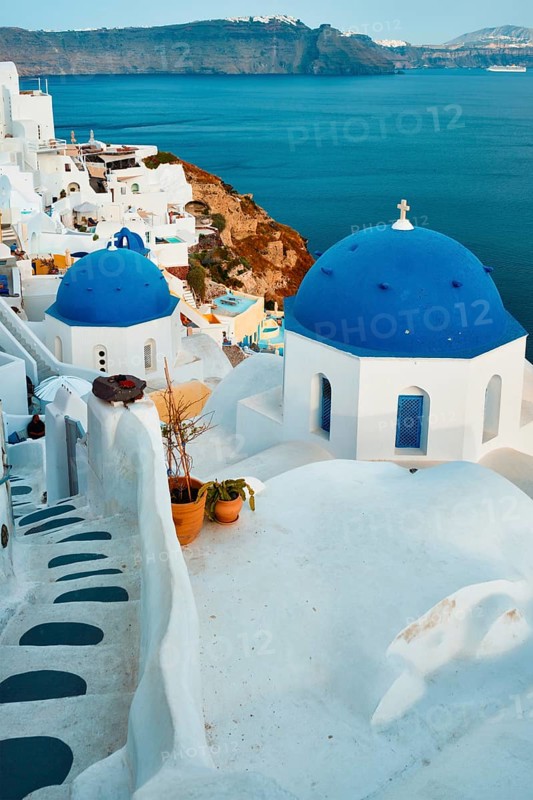 Famous view from viewpoint of Santorini Oia village with blue dome of whitewashed greek orthodox Christian church of traditional greek architecture