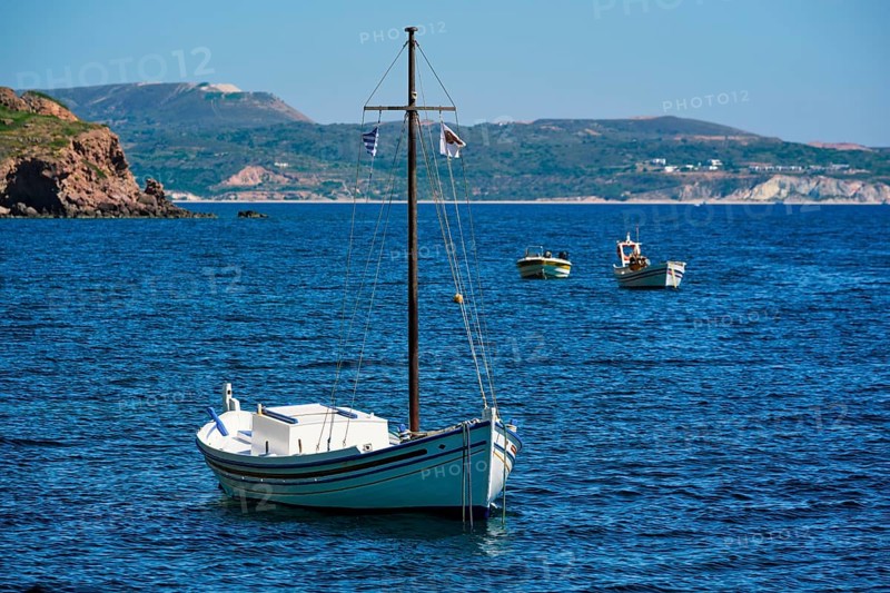 Traditional greek fishing boat in the Aegean sea with greek flag