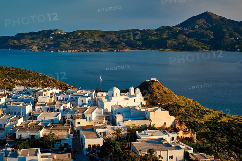 View of Plaka village on Milos island with traditional greek white houses with Greek Orthodox christian churck on sunset