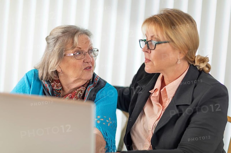 Woman helping senior adult lady on laptop computer