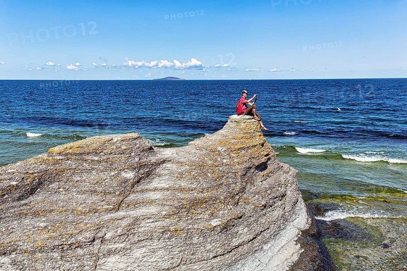 Hiker sitting on limestone pillar photographing landscape